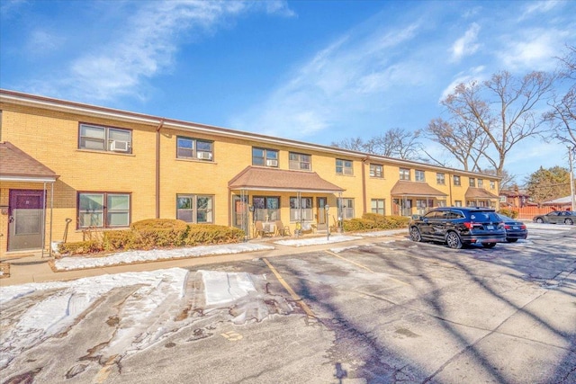 multi unit property featuring covered porch, uncovered parking, and brick siding