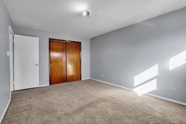 unfurnished bedroom featuring carpet floors, a closet, and baseboards