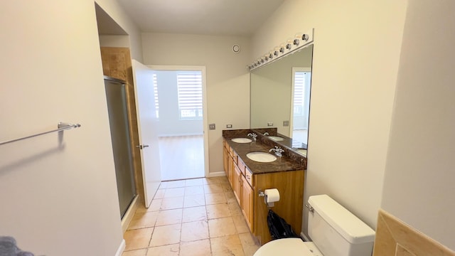 bathroom with a sink, a shower stall, toilet, and double vanity