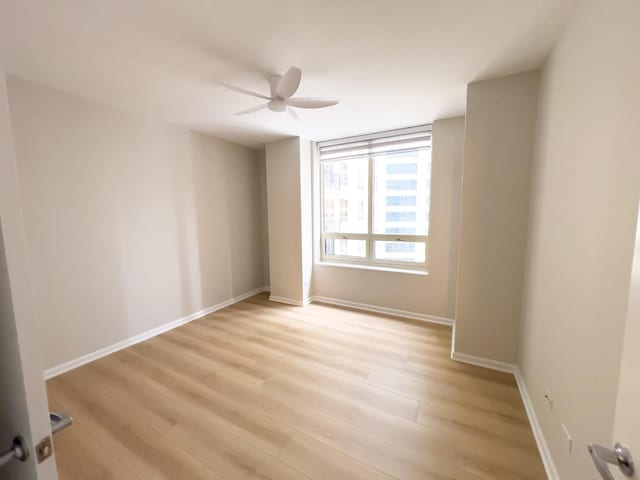 empty room with light wood finished floors, ceiling fan, and baseboards