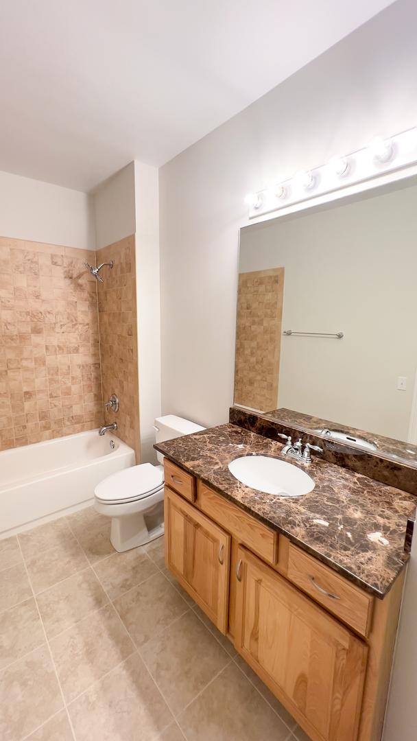 full bathroom with toilet, tile patterned flooring, vanity, and shower / bathing tub combination