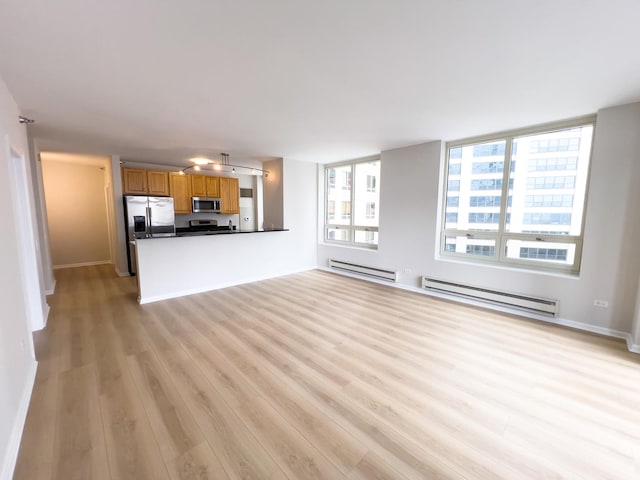 unfurnished living room with a baseboard heating unit, baseboards, and light wood finished floors