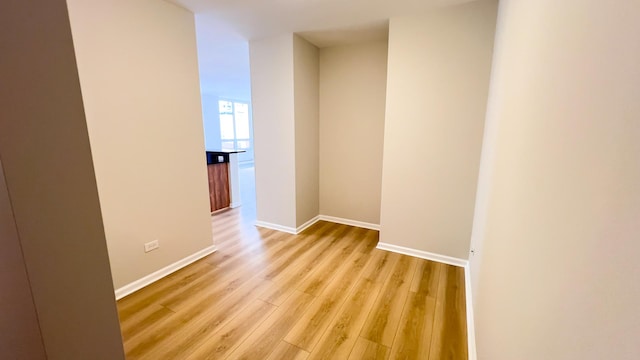 hall with light wood-style flooring and baseboards