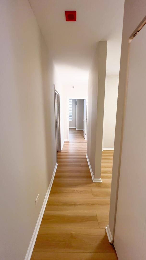 hallway featuring light wood-type flooring and baseboards