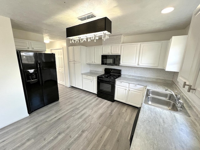 kitchen with light wood-style flooring, a sink, white cabinets, backsplash, and black appliances