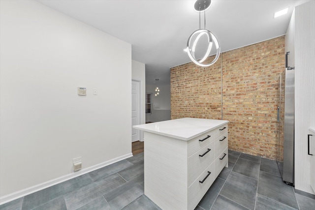 interior space with light countertops, freestanding refrigerator, a kitchen island, brick wall, and modern cabinets