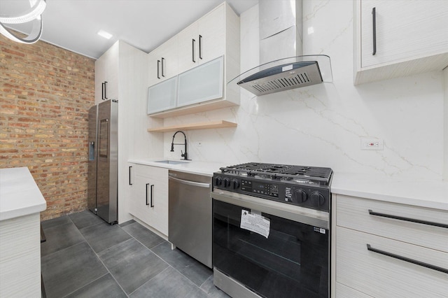 kitchen featuring wall chimney range hood, stainless steel appliances, a sink, and light countertops