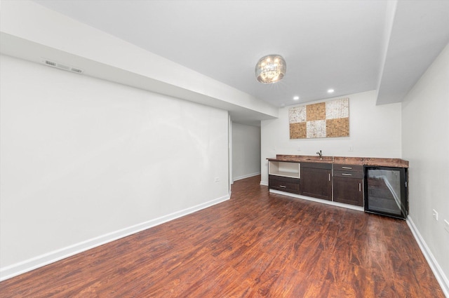 bar with beverage cooler, visible vents, baseboards, indoor wet bar, and dark wood finished floors