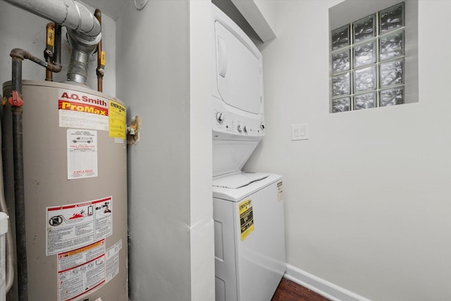 washroom with stacked washing maching and dryer, baseboards, laundry area, and gas water heater