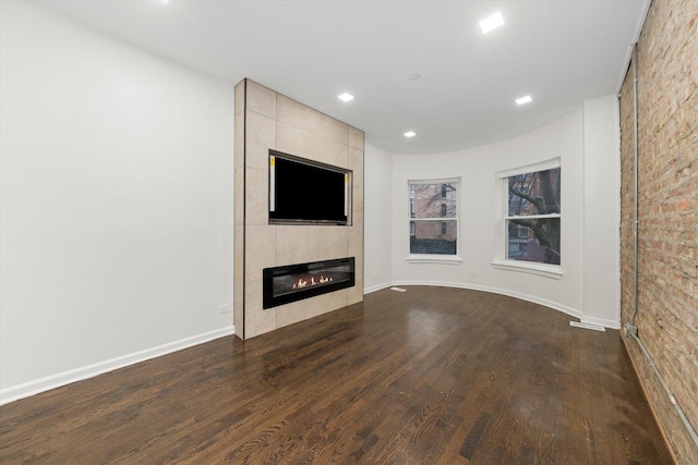 unfurnished living room with dark wood-type flooring, a fireplace, recessed lighting, and baseboards