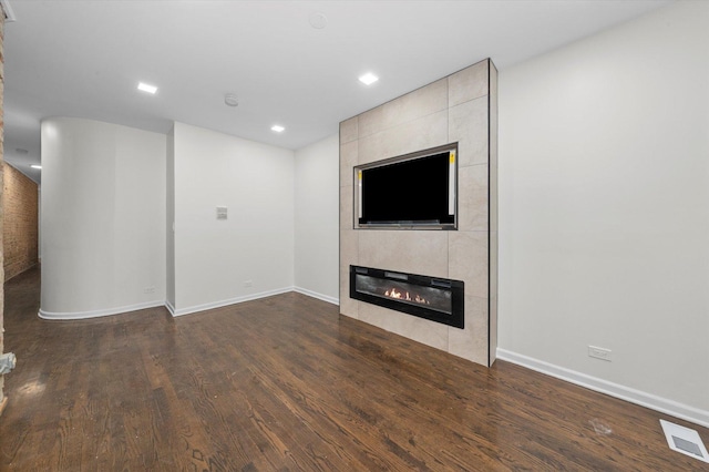 unfurnished living room featuring baseboards, a fireplace, visible vents, and wood finished floors