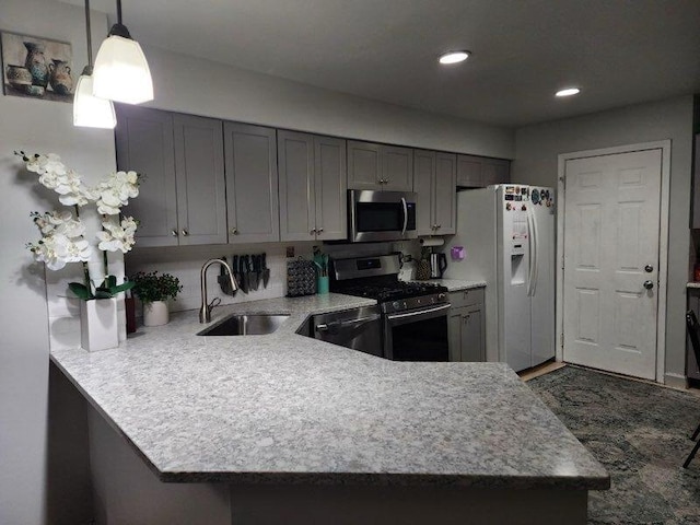 kitchen with stainless steel appliances, hanging light fixtures, a sink, and light countertops