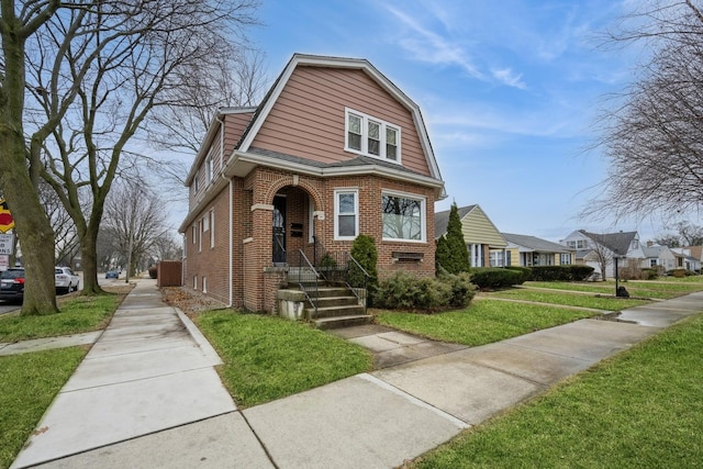 colonial inspired home with brick siding, a front lawn, and a gambrel roof