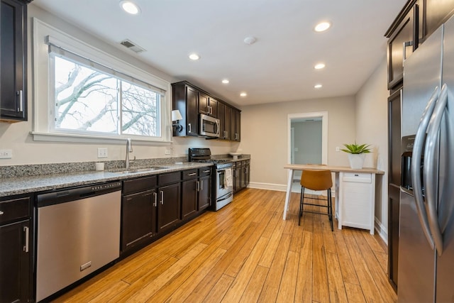 kitchen featuring recessed lighting, stainless steel appliances, a sink, visible vents, and light wood-type flooring