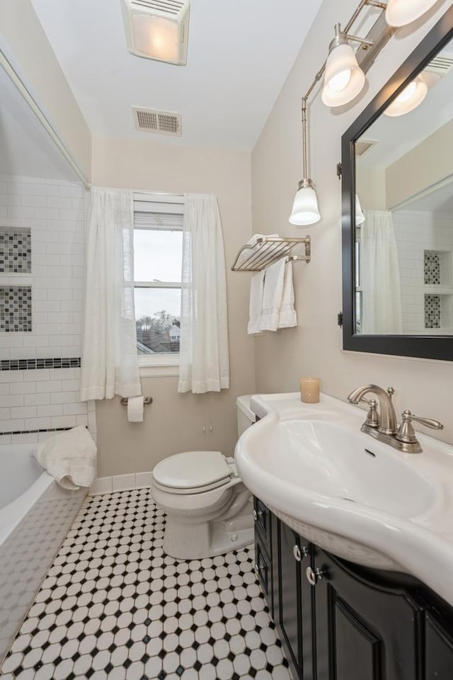 full bath featuring toilet, vanity, visible vents, and baseboards