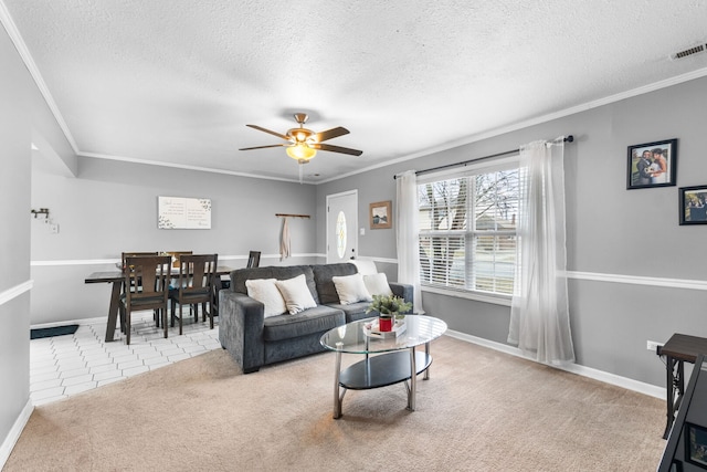 tiled living area featuring ceiling fan, a textured ceiling, ornamental molding, and carpet flooring