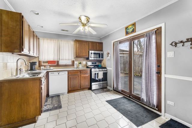 kitchen with a ceiling fan, a sink, stainless steel appliances, light countertops, and backsplash