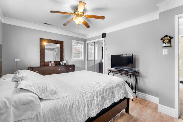 bedroom featuring wood finished floors, visible vents, baseboards, ornamental molding, and a closet