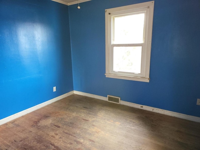 spare room featuring baseboards, visible vents, and wood finished floors