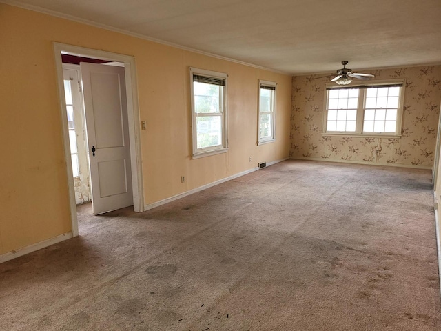 empty room featuring light carpet, ornamental molding, baseboards, and wallpapered walls