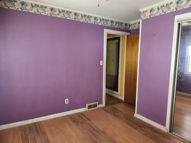 unfurnished room with visible vents, baseboards, and wood finished floors