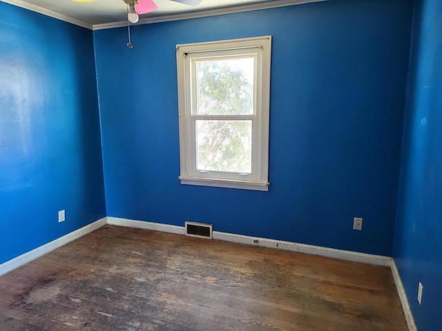 empty room with baseboards, wood finished floors, visible vents, and crown molding