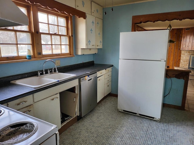 kitchen featuring freestanding refrigerator, dishwasher, dark countertops, and a sink