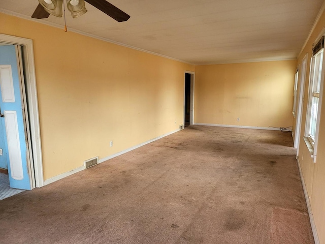 empty room with light colored carpet, visible vents, crown molding, and baseboards