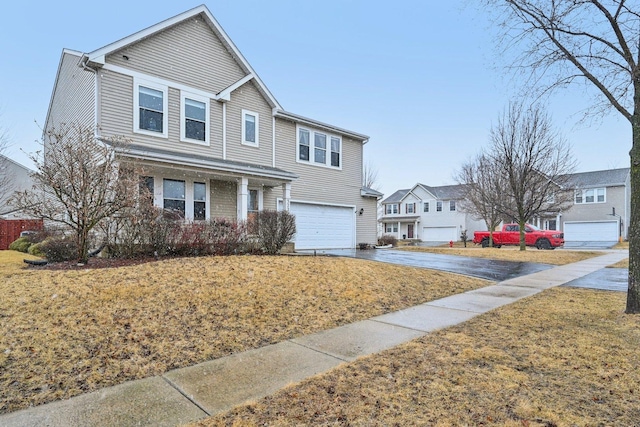 traditional-style house featuring a garage, driveway, a front yard, and a residential view