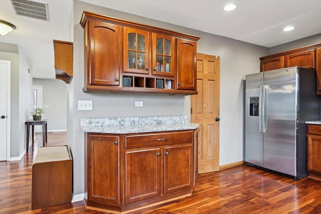 kitchen featuring stainless steel fridge, visible vents, dark wood finished floors, and light stone counters