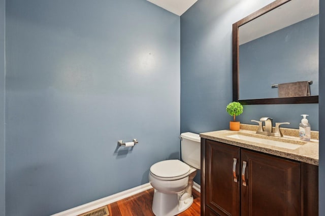 bathroom with baseboards, vanity, toilet, and wood finished floors