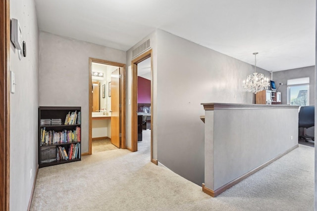 hallway with baseboards, carpet floors, visible vents, and an inviting chandelier