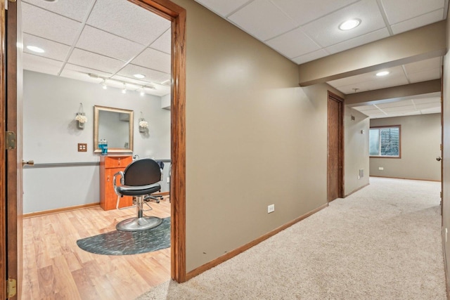 hall with a drop ceiling, wood finished floors, baseboards, carpet, and track lighting