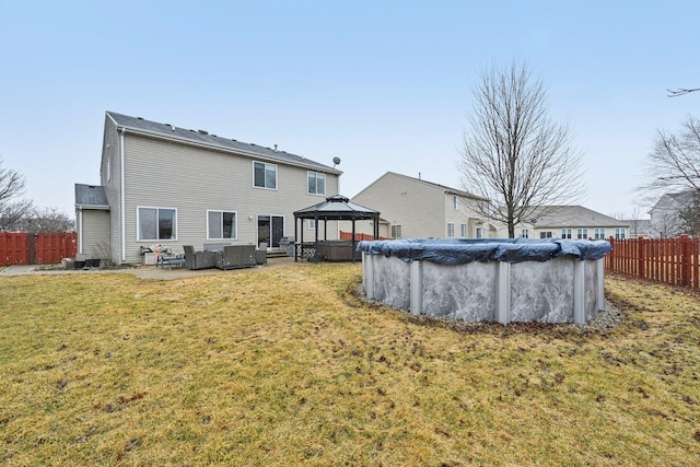 back of property featuring fence, a lawn, a fenced in pool, and a gazebo