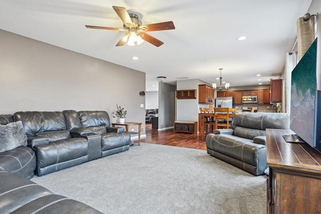 living area with recessed lighting, dark colored carpet, dark wood-type flooring, baseboards, and ceiling fan with notable chandelier