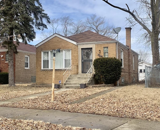 bungalow featuring central AC, brick siding, fence, and a chimney