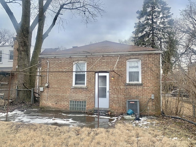 rear view of property with entry steps, central AC, brick siding, and fence