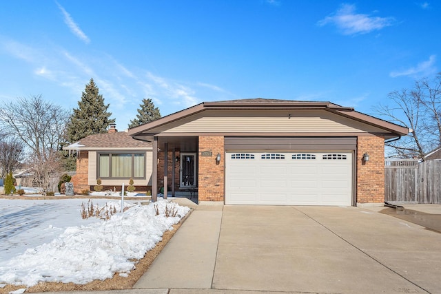 view of front of house featuring a garage, concrete driveway, brick siding, and fence