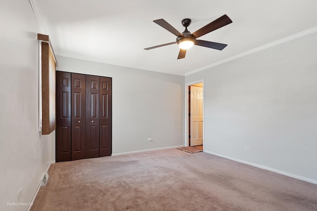 unfurnished bedroom with a closet, baseboards, crown molding, and light colored carpet