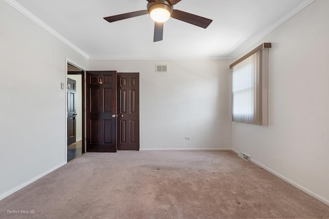 spare room with ornamental molding, visible vents, light carpet, and baseboards