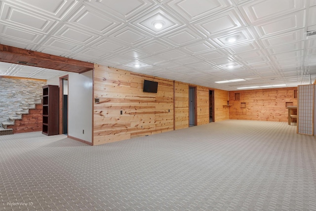 finished below grade area featuring an ornate ceiling, carpet, and wooden walls