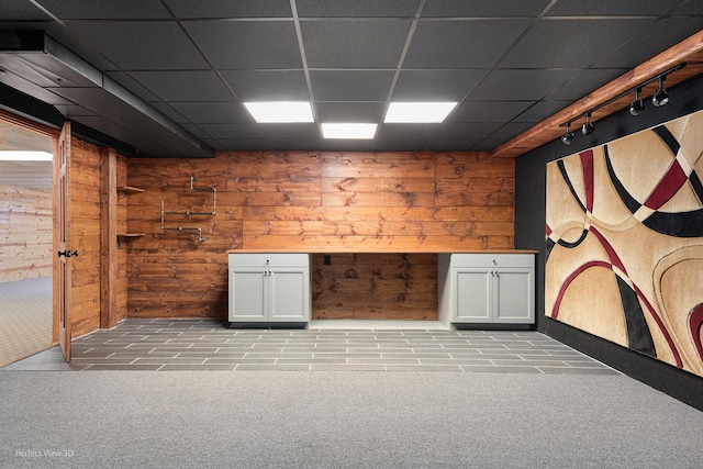 spare room featuring wooden walls, a drop ceiling, track lighting, and light colored carpet