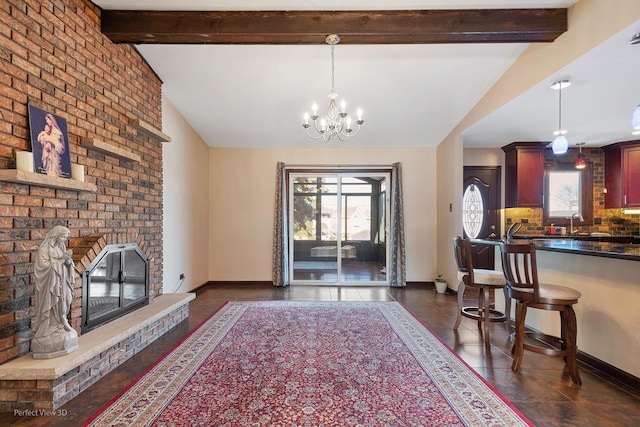 interior space featuring vaulted ceiling with beams, a brick fireplace, and baseboards