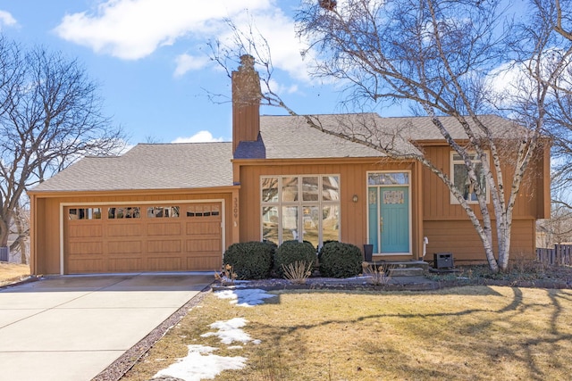 view of front facade with a chimney, concrete driveway, entry steps, a front yard, and a garage