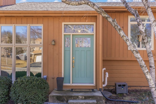 view of exterior entry with a shingled roof