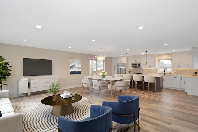 living area featuring baseboards, recessed lighting, a chandelier, and light wood-style floors