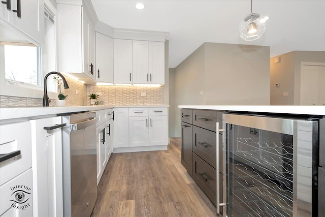 kitchen featuring beverage cooler, white cabinetry, light countertops, dishwasher, and pendant lighting