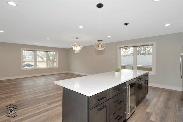 kitchen with wine cooler, open floor plan, decorative light fixtures, light countertops, and light wood-style floors