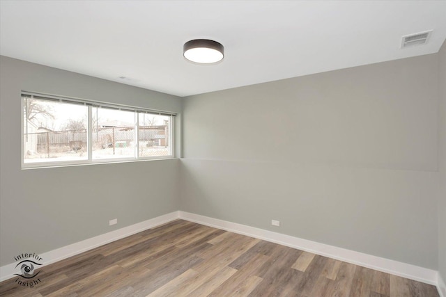 empty room featuring baseboards, visible vents, and wood finished floors