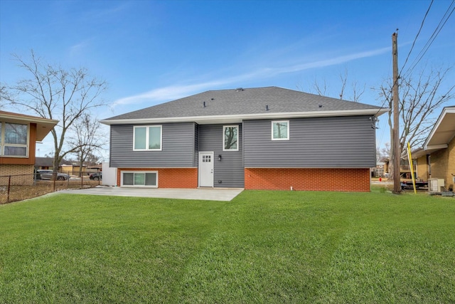 rear view of property with roof with shingles, fence, a yard, a patio area, and brick siding